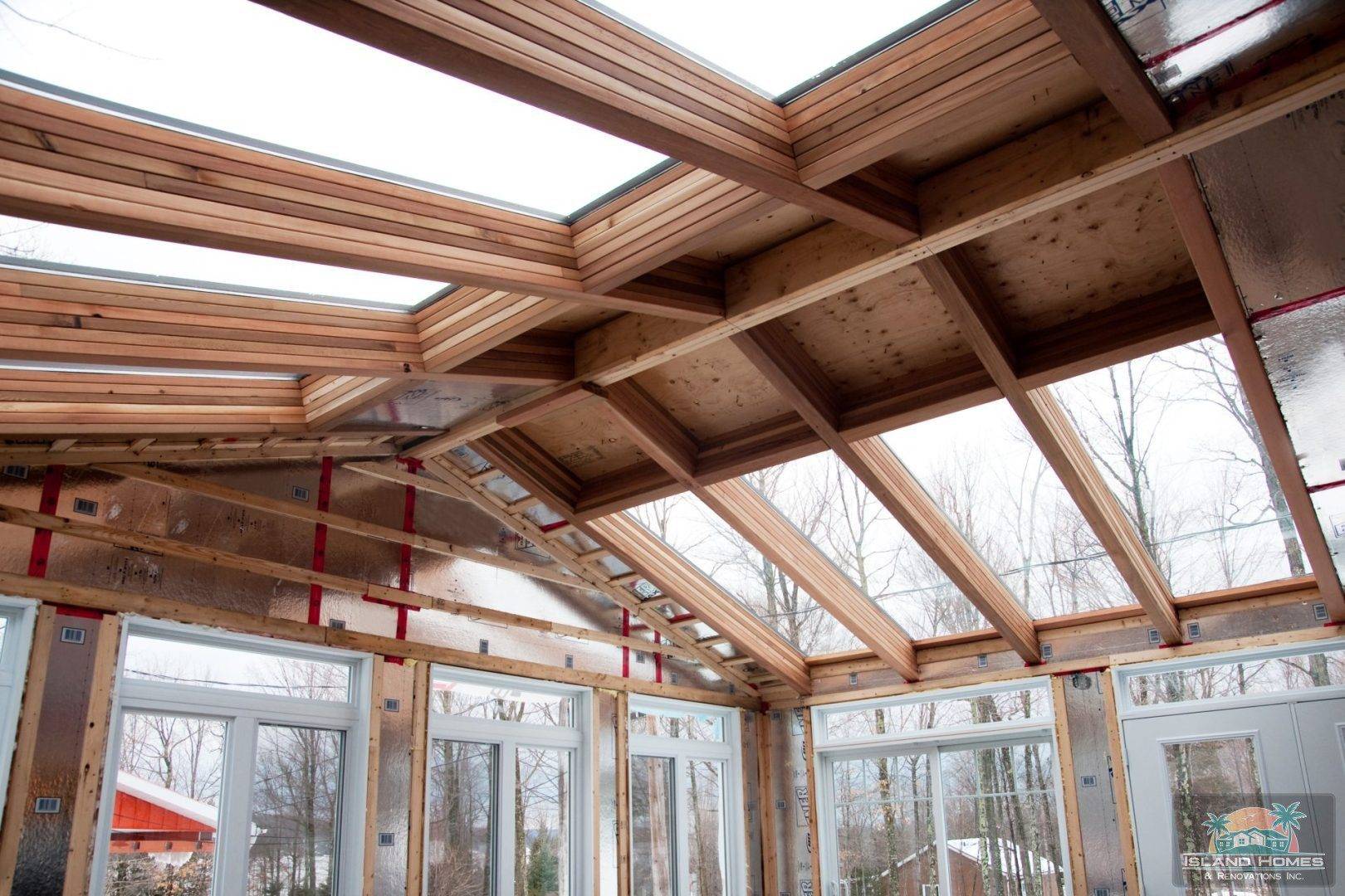 A sunroom featuring wooden beams and skylights, creating a bright and airy atmosphere.