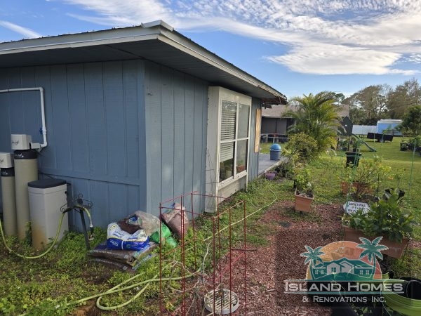 A small house surrounded by a yard and a vibrant garden filled with various plants and flowers.