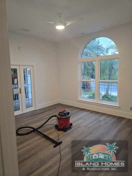 A room featuring wooden floors with a vacuum cleaner positioned in the center, ready for use.