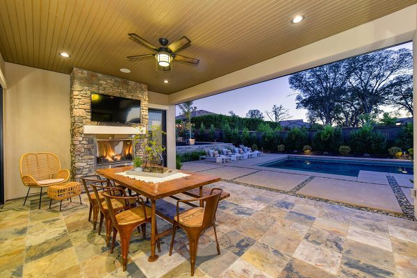 Dining area, fireplace, and pool to a peaceful and inviting outdoor living space at dusk.