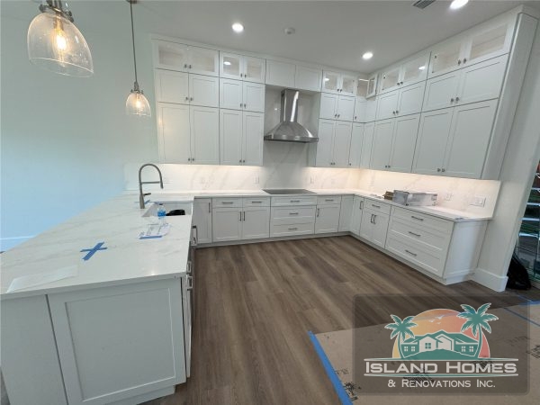 A modern kitchen featuring white cabinets and countertops, creating a bright and clean aesthetic.