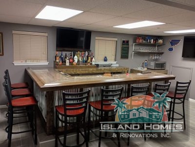 A stylish bar with a counter and chairs, set in a spacious room, inviting guests to relax and enjoy their drinks.