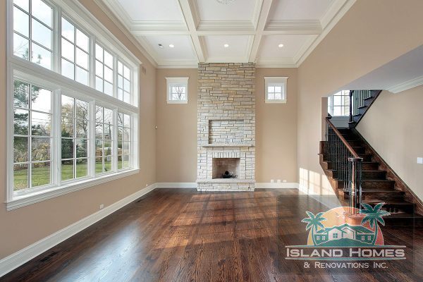 A large, vacant room showcasing hardwood flooring and a fireplace, highlighting its potential for various uses.