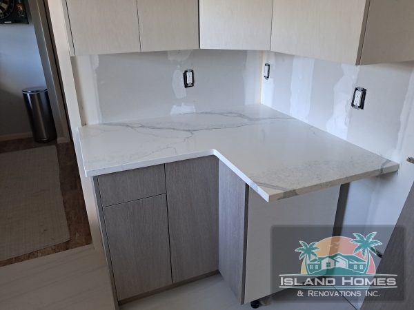 A contemporary kitchen interior with gray walls complemented by white cabinets, offering a bright and airy feel.