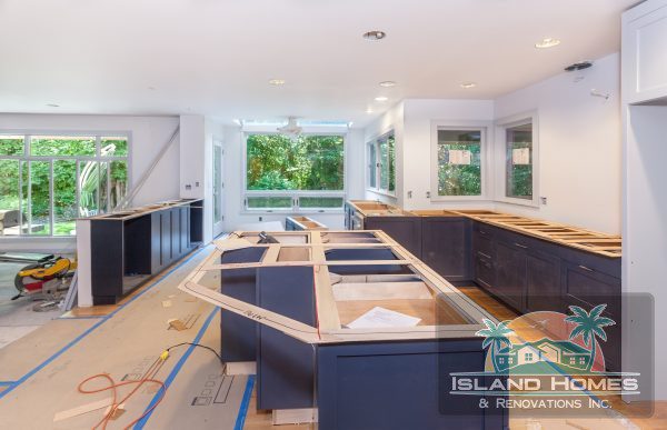 A kitchen under construction featuring blue cabinets and countertops, showcasing unfinished walls and tools scattered around.