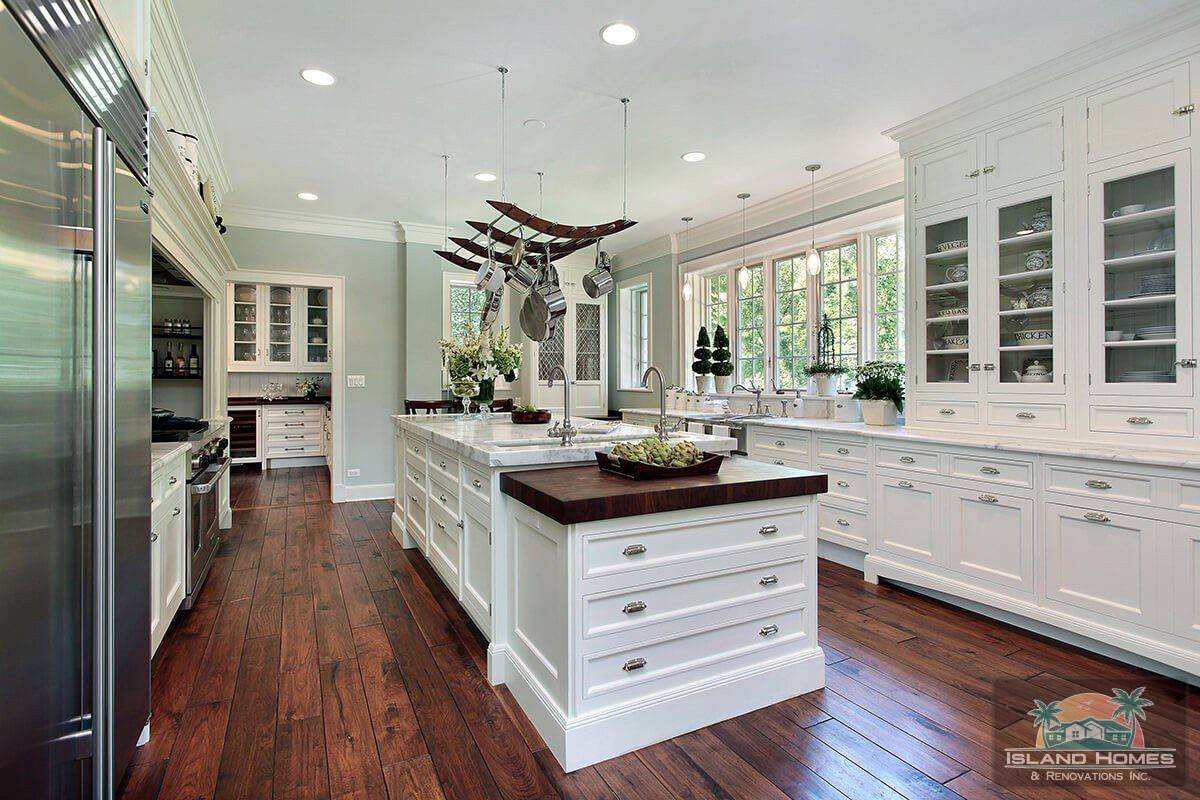 A spacious kitchen featuring white cabinets and elegant hardwood floors.